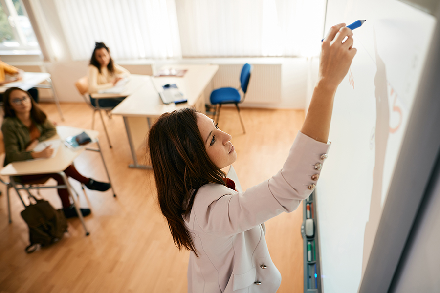 High school teacher writing on interactive whiteboard during a class.