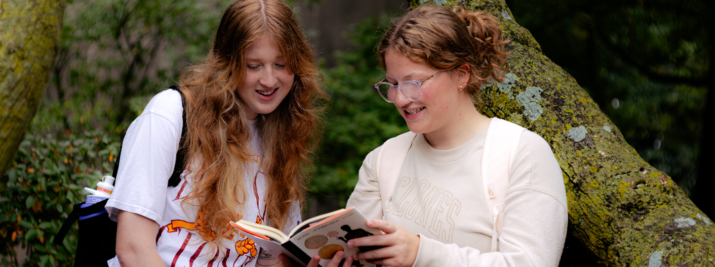 Two students look over an English text book